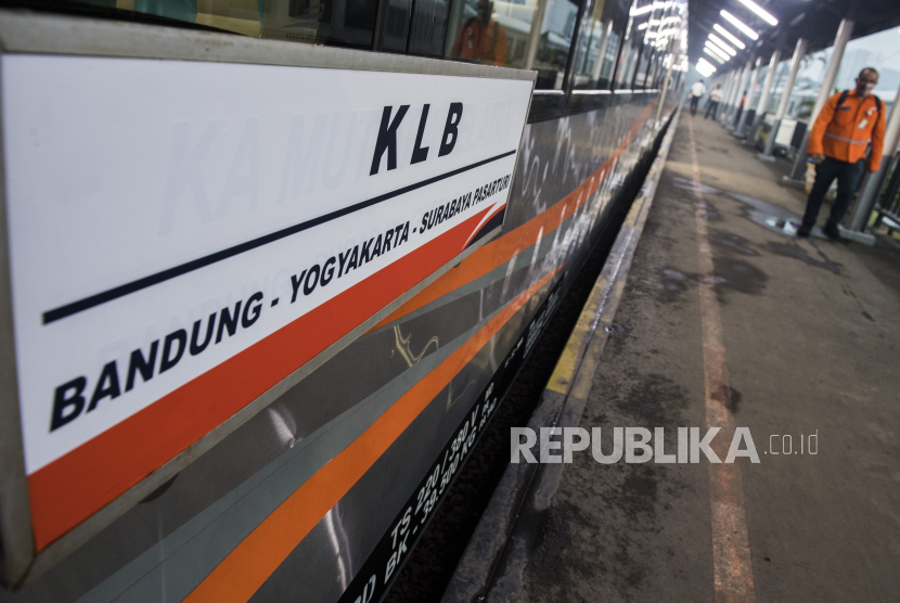 Penumpang melintas di samping  Kereta Api Luar Biasa (KLB) jurusan Stasiun Bandung-Surabaya Pasar Turi.