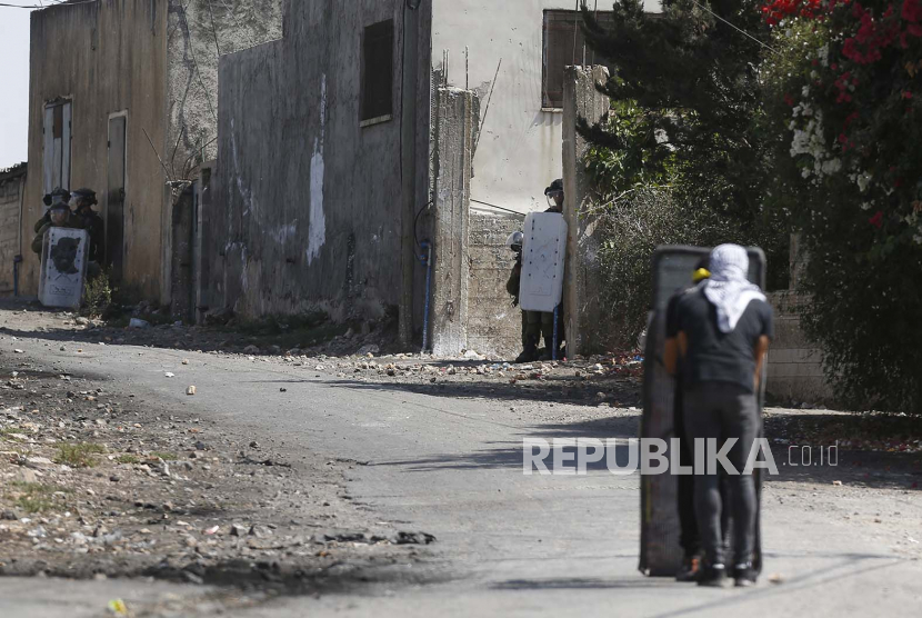 Para pengunjuk rasa Palestina menyaksikan pasukan Israel selama bentrokan setelah demonstrasi menentang pemukiman Israel di tanah desa Kafr Qadoum, dekat kota Nablus, Tepi Barat, 23 September 2022.