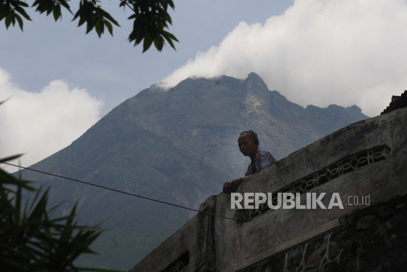 Seorang warga beraktivitas dengan berlatar belakang Gunung Merapi di Klakah, Selo, Boyolali, Jawa Tengah.