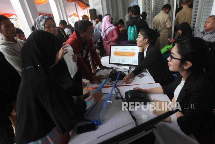 Panitia pelaksana melayani antrean wali murid saat pendaftaran PPDB Online di SMKN 1, Jakarta, Selasa (26/6).
