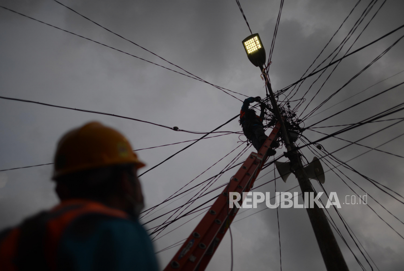 Petugas PLN memperbaiki aliran listrik yang terputus. Komisi VII ingin warga miskin bebas biaya listrik di tengah merebaknya wabah corona.
