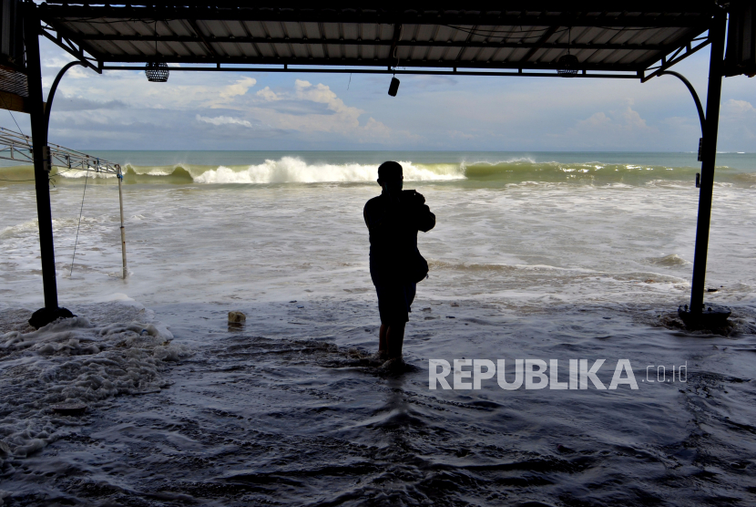 Seorang warga diterjang gelombang pasang air laut di kawasan Pantai Jimbaran, Badung, Bali, Kamis (28/5/2020). Gelombang tinggi dan pasang air laut yang terjadi di kawasan perairan tersebut sejak Rabu (27/5), merusak sejumlah bangunan kafe serta mengakibatkan nelayan setempat tidak dapat melaut