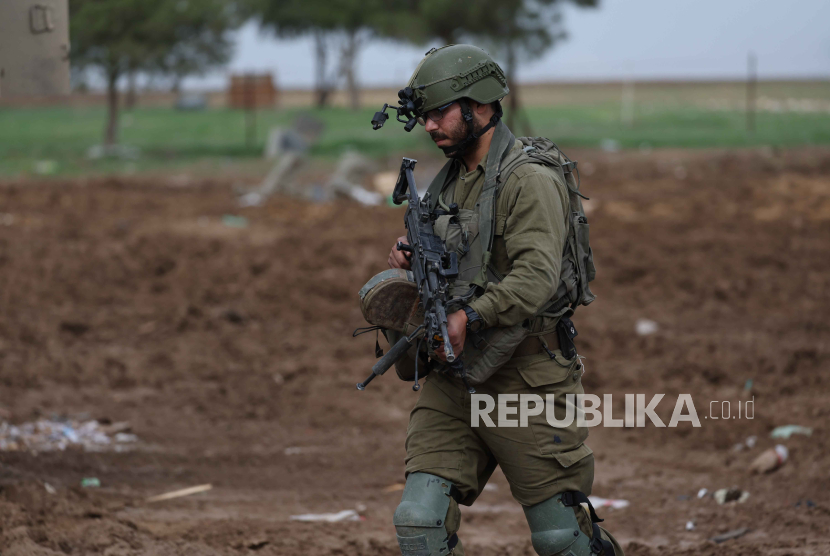 Seorang tentara Israel berjalan di dekat perbatasan Gaza pada 14 December 2023.