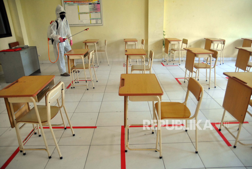 Petugas sekolah menyemprot cairan disinfektan pada kelas yang telah diatur jarak antar siswa di SMK Kosgoro, Kota Bogor, Jawa Barat. Dinas Pendidikan Kota Bogor baru akan mulai verifikasi kesiapan sekolah lakukan tatap muka.