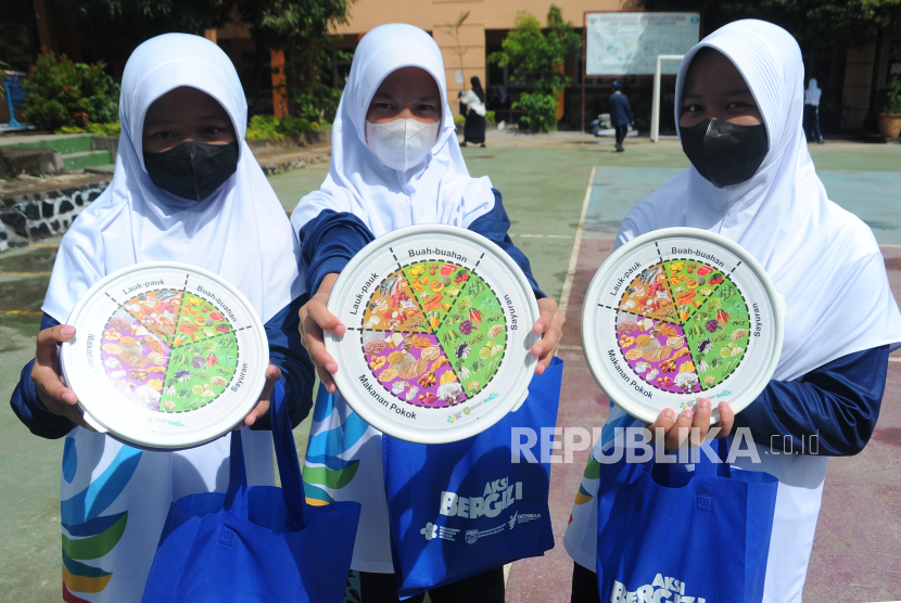 Sejumlah siswa menunjukkan kotak makan yang berisi menu bergizi seimbang pada kegiatan Gerakan Nasional Aksi Bergzi di SMP Negeri 19 Palembang, Sumsel, Rabu (26/10/2022).