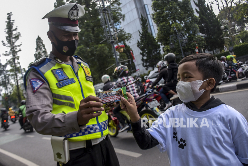 Seorang anak memberikan makanan ringan dan pesan tolak kekerasan kepada petugas kepolisian.