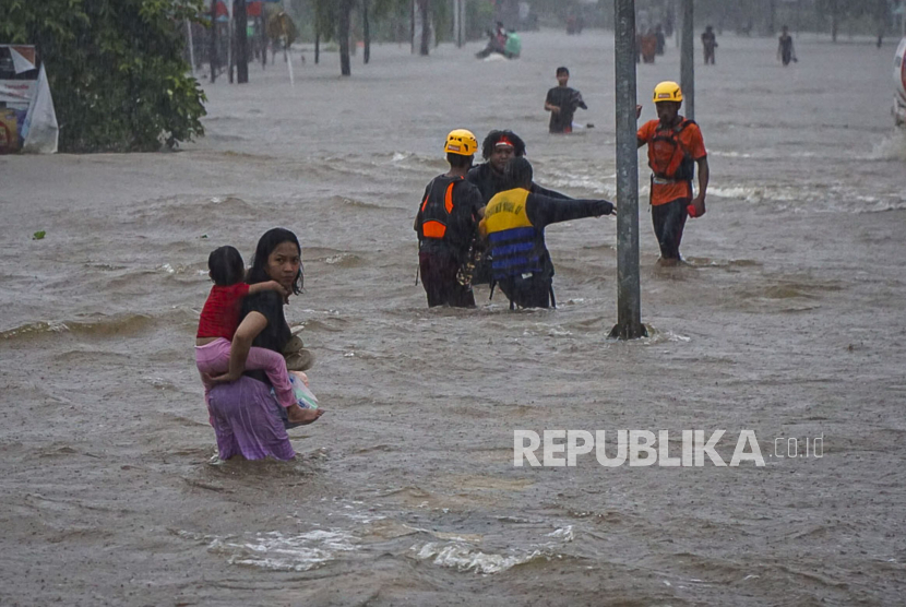 Sejumlah warga melintasi Jalan Lintas Melawi yang terdampak banjir di Ladang, Kabupaten Sintang, Kalimantan Barat, Jumat (12/11/2021). Banjir yang melanda 12 kecamatan tersebut belum juga surut selama tiga pekan terakhir akibat curah hujan yang tinggi, sementara pendistribusian bantuan masih terkendala di sejumlah wilayah karena sulitnya akses menuju lokasi. 