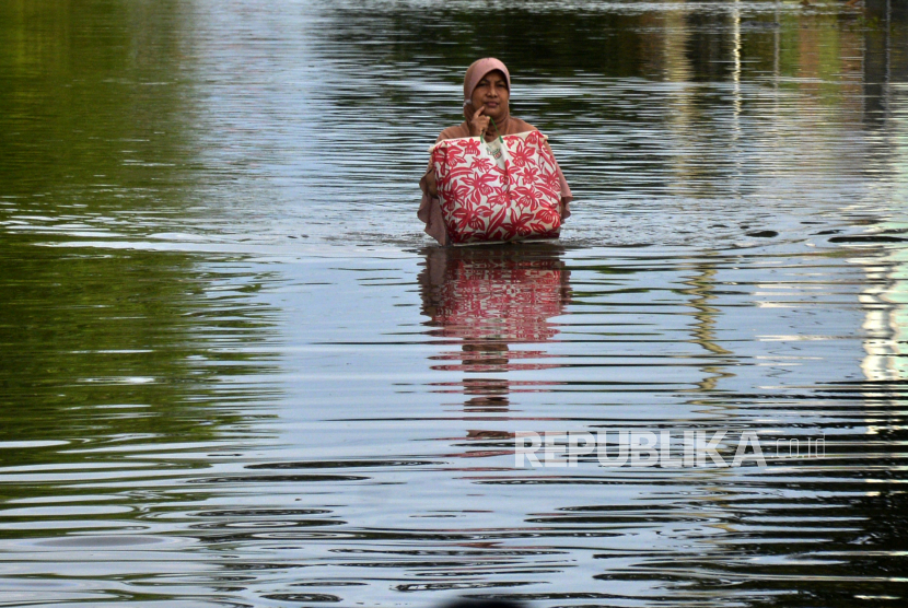 Warga berusaha menyeberangi jalan yang tergenang air di Makassar, Sulawesi Selatan. Dinas Sosial Makassar, Sulawesi Selatan, menyiapkan 1.000 paket makanan siap saji untuk korban banjir yang saat ini masih bertahan di posko pengungsian. (ilustrasi)