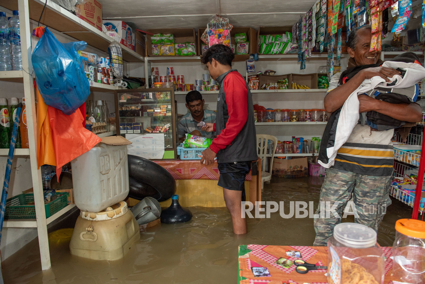 Warga berbelanja di warung yang tergenang banjir Kampung Tibang, Kecamatan Pidie, Kabupaten Pidie, Aceh, Minggu (22/1/2023). Banjir tersebut disebabkan tingginya intensitas hujan di kawasan tersebut dan buruknya drainase. 