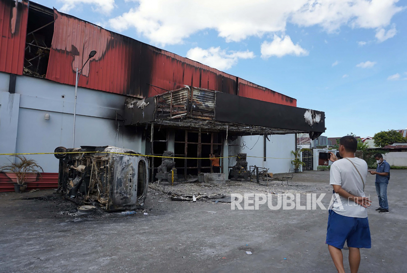 Seorang laki-laki berdiri di luar klub malam yang dibakar setelah dua kelompok bentrok hingga terjadi pembakaran Karaoke Doubel0 di Kota Sorong, Provinsi Papua Barat, Selasa (25/1/2022). 