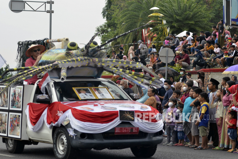 Warga menonton Kendaraan hias yang melintas saat mengikuti acara Pawai Drumband di Kota Bandar Lampung, Lampung, Ahad (14/8/2022). Pawai Drumband tersebut dilaksanakan dalam rangka menyemarakkan HUT Kemerdekaan RI ke-77 dan diikuti oleh 900 orang pelajar SMA di Lampung. 