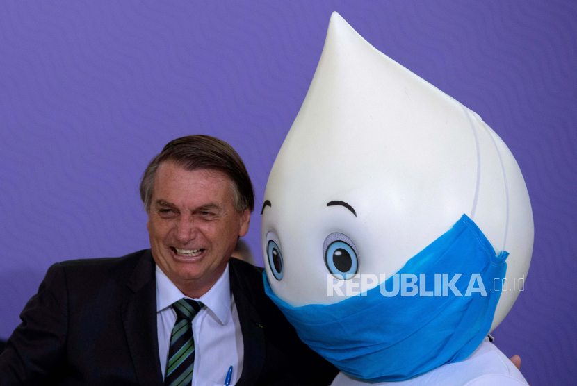 Presiden Brasil Jair Bolsonaro berpose untuk foto dengan maskot Ze Gotinha, karakter tradisional di Brasil yang diciptakan untuk meningkatkan kesadaran tentang vaksin, selama peluncuran Rencana Vaksinasi Nasional melawan Covid-19, di Istana Planalto di Brasilia, Brasil, 16 Desember 2020