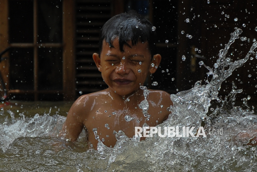 Anak bermain saat banjir di Jakarta (ilustrasi). Pemprov DKI Jakarta memperketat pemantauan terhadap potensi penyebaran penyakit yang timbul akibat banjir.
