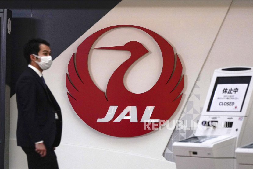 Seorang staf berjalan melewati logo Japan Airlines di Bandara Haneda Tokyo, Jepang, 01 Februari 2021. Japan Airlines akan pensiunkan 13 pesawat tipe Boeing 777 dengan mesin Pratt & Whitney setahun lebih awal dari yang direncanakan. 