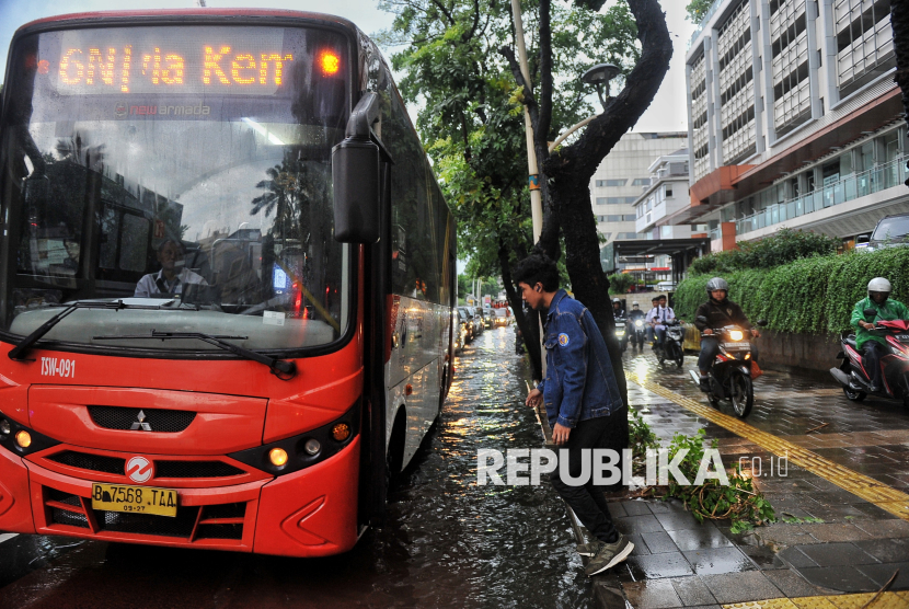 Penumpang menghindari genangan air saat akan menaiki transjakarta di Jalan Kemang Raya, Jakarta Selatan, Selasa (5/11/2024). BMKG memprakirakan Jakarta turun hujan sepanjang hari.