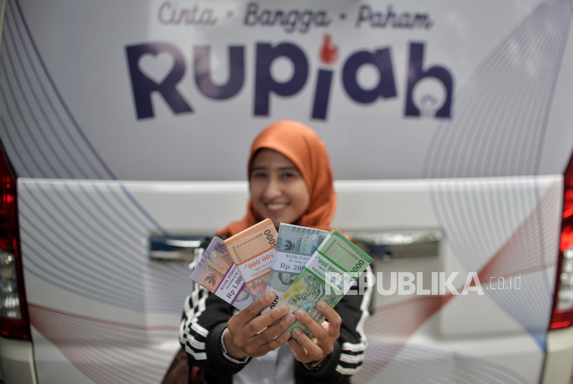 Warga menunjukan uang tunai baru usai menukarkannya di layanan kas keliling  Bank Indonesia di kawasan Pasar Tebet Barat, Jakarta, Selasa (28/3/2023). 