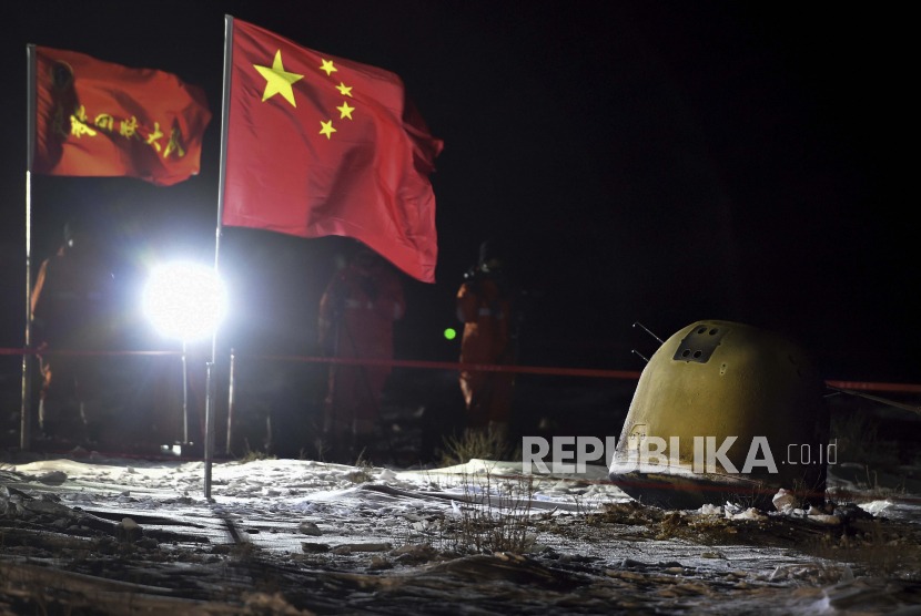  Dalam foto yang dirilis oleh Kantor Berita Xinhua ini, anggota kru pemulihan memfilmkan kapsul penyelidikan Chang