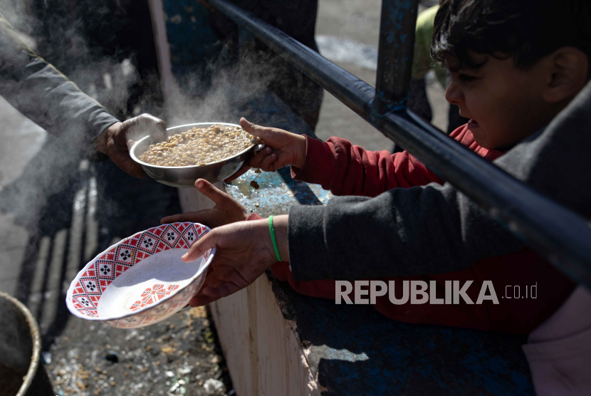 Anak-anak pengungsi Palestina memegang pot mereka saat menerima bantuan makanan yang diberikan oleh kelompok pemuda Palestina, di kamp pengungsi Rafah, Jalur Gaza selatan, (1/2/2024).