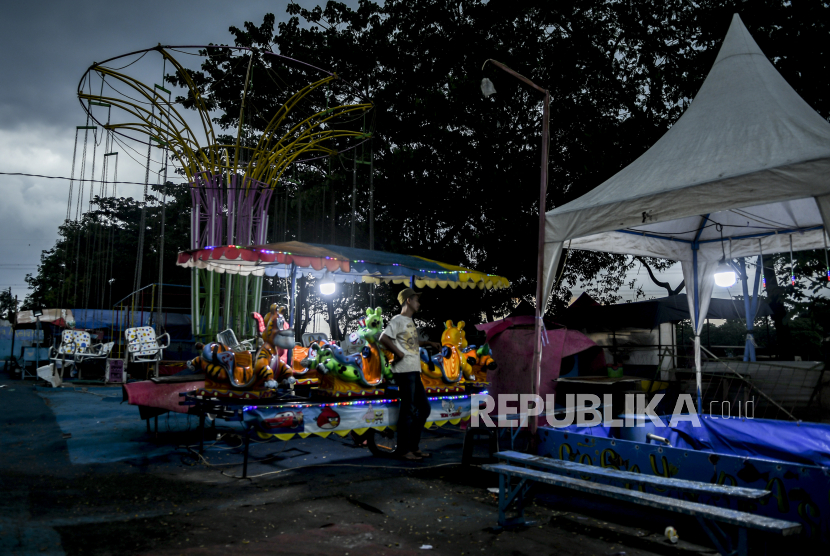 Penjaga wahana berdiri di lokasi Pasar Malam yang tutup di Kanal Banjir Timur, Jakarta Timur, Minggu (10/5/2020). Pasar malam yang berdiri sejak tahun 2015 tersebut terpaksa berhenti beroperasi dan menutup wahananya dikarenakan tidak adanya pengunjung akibat  pemberlakuan Pembatasan Sosial Berskala Besar (PSBB) guna menekan penyebaran COVID-19 di Ibu Kota