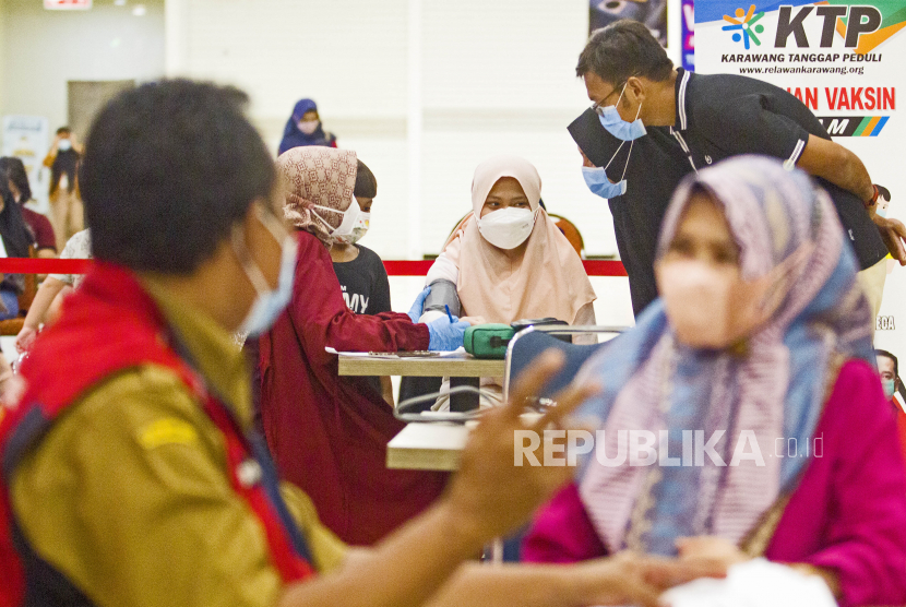 Petugas memeriksa kesehatan warga sebelum vaksinasi Covid-19 di kawasan Galuh Mas, Karawang, Jawa Barat, Senin (7/2/2022).