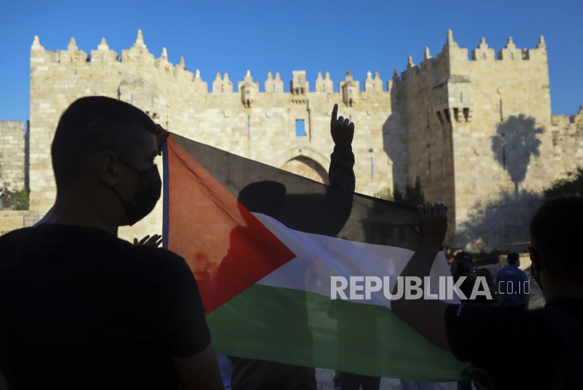 Dalam foto arsip 19 Juni 2021 ini, para demonstran Palestina mengibarkan bendera Palestina selama protes di gerbang Damaskus di luar Kota Tua Yerusalem. Khawatir Serangan Israel, Ramadhan Warga Palestina Diselimuti Ketakutan