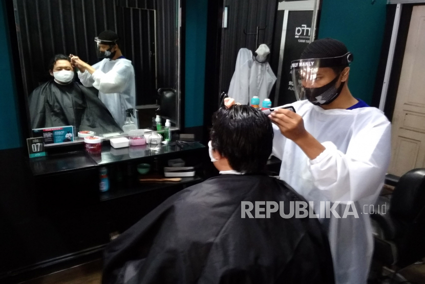 Pegawai menggunakan masker dan pelindung wajah mencukur rambut pengunjung di Arfa Barbershop, Yogyakarta, Senin (8/6). Bisnis barbershop cukup banyak dilirik pebisnis pemula.