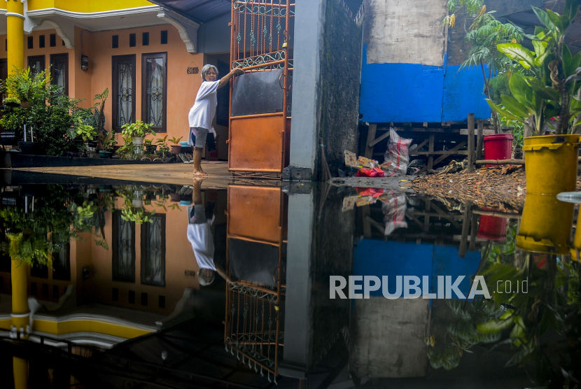 Seorang warga membuka gerbang rumah saat terjadi banjir di kawasan Duren Sawit, Jakarta, Selasa (15/3/2022). Menurut warga, banjir setinggi 40 cm hingga 80 cm yang telah merendam pemukiman hingga sepekan tersebut diakibatkan saluran air dari Waduk Haji Dogol ke Kanal Banjir Timur (KBT) yang tersumbat tanah. Republika/Putra M. Akbar