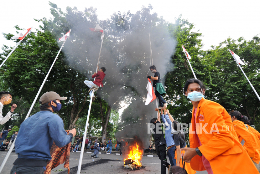 Beberapa mahasiswa menurunkan bendera Merah Putih yang terpasang di halaman depan Kantor Gubernur Jambi saat unjuk rasa menolak UU Cipta Kerja di Kantor DPRD Jambi, Jambi, Senin (12/10/2020). Aksi yang melibatkan ribuan mahasiswa dari sejumlah perguruan tinggi di Jambi tersebut berakhir ricuh. 