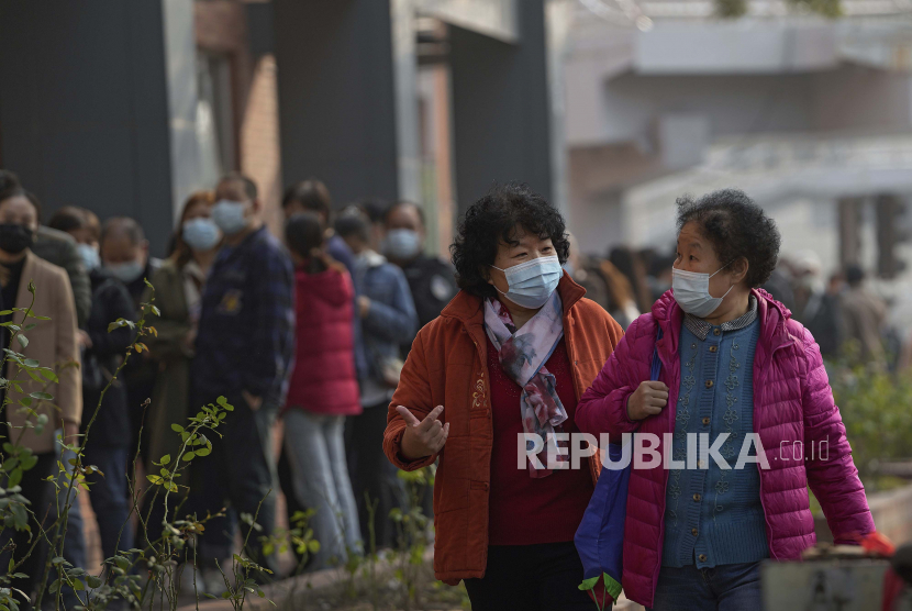  Warga memakai masker untuk membantu mengekang penyebaran SARS-CoV-2 berjalan melalui antrean penerima suntikan booster vaksin Covid-19 di Beijing, China, Senin, 25 Oktober 2021. China kini sedang menerapkan kebijakan nol penularan.