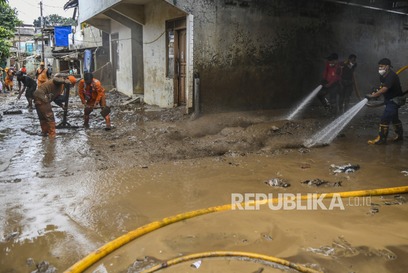 Petugas pemadam kebakaran bersama warga menyemprotkan air untuk membersihkan endapan lumpur sisa banjir di kawasan Pejaten Timur, Pasar Minggu, Jakarta, Selasa (9/2/2021). Banjir yang melanda permukiman warga di kawasan tersebut berangsur surut, dan warga mulai membersihkan rumah dari endapan lumpur sisa banjir. 
