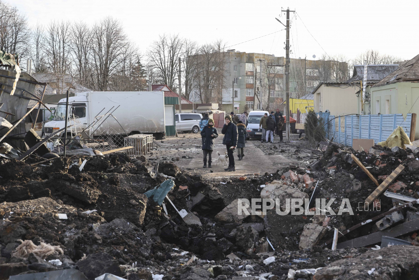 Warga Ukraina berdiri di dekat kawah peluru di pasar lokal yang rusak setelah penembakan menghantam kota Shevchenkove, wilayah Kharkiv, timur laut Ukraina, 09 Januari 2023, di tengah invasi Rusia. 