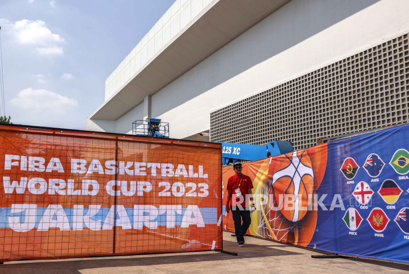 Seorang pekerja turnamen berjalan melewati spanduk di luar stadion Indonesia Arena saat Piala Dunia Bola Basket FIBA 2023 di Jakarta. 