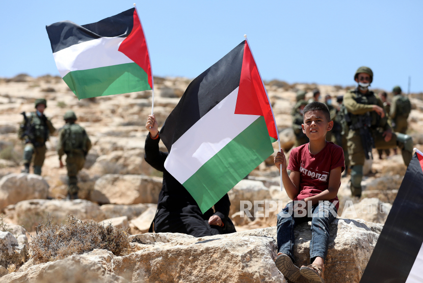  Warga Palestina mengibarkan bendera selama protes di Tepi Barat, di desa Yatta, dekat Hebron, 21 Agustus 2020. Warga Palestina memprotes perjanjian perdamaian untuk membangun hubungan diplomatik antara Israel dan Uni Emirat Arab.