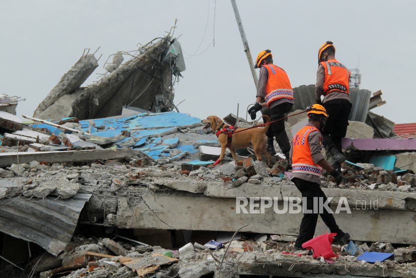 Anggota polisi dengan bantuan Unit Satwa K9 Mades Polri  di Rumah Sakit Mitra Manakarra yang runtuh akibat gempa bumi di Mamuju, Sulawesi Barat, Ahad (17/1/2021). Memasuki hari ke tiga pasca gempa bumi tim SAR, TNI dan Polri masih melakukan pencarian korban di beberapa lokasi. 