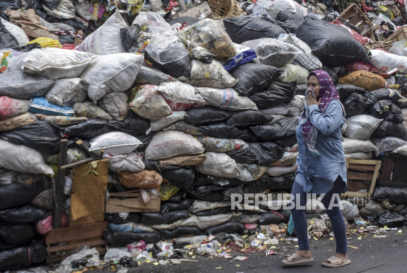Warga melintas di samping tumpukan sampah di TPS Pasar Sederhana, Sukajadi, Kota Bandung.