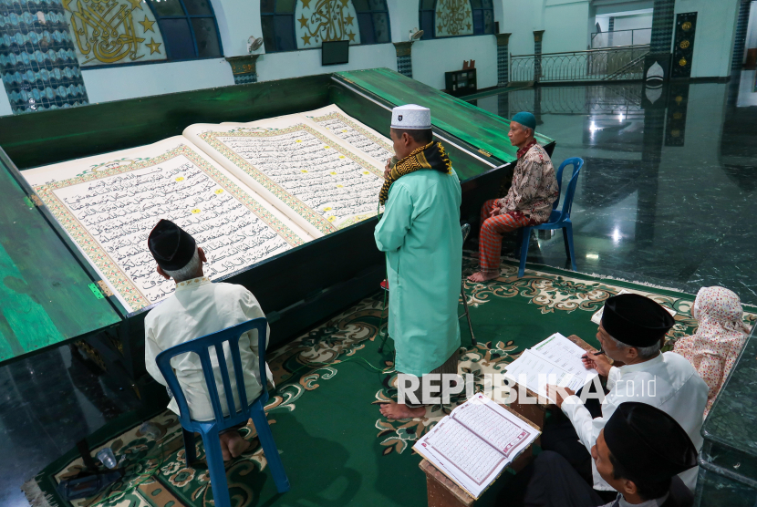 Warga tadarus menggunakan Al Quran raksasa di Masjid Agung Baiturrahman, Banyuwangi, Jawa Timur, Rabu (5/3/2025). Tradisi tadarus Al Quran raksasa berukuran 142 x 210 centimeter yang ditulis tangan oleh Abdul Karim pada tahun 2010 itu membutuhkan dua orang petugas untuk membalikkan setiap lembar Al Quran ketika mencapai halaman berikutnya. 