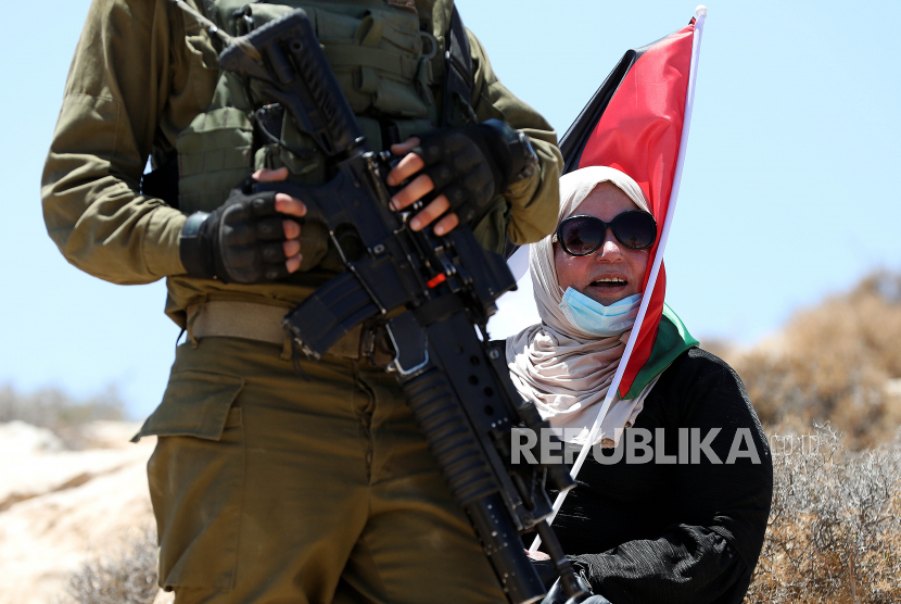 China Peringati Hari Solidaritas dengan Rakyat Palestina. Seorang wanita Palestina memegang bendera saat protes di Tepi Barat, di desa Yatta, dekat Hebron, 21 Agustus 2020. Warga Palestina memprotes perjanjian perdamaian untuk membangun hubungan diplomatik antara Israel dan Uni Emirat Arab.