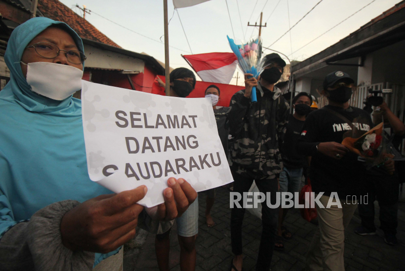 Warga menyambut kedatangan Agus H S (kanan) dan Nuryanto L (ketiga kanan) yang pulang dari Asrama Haji, Surabaya, Jawa Timur, Selasa (23/6). Tingkat penularan Covid-19 masih tinggi di Surabaya Raya.