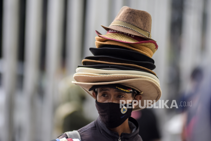 Seorang pedagang mengenakan masker di Jalan Asia Afrika, Kota Bandung, Rabu (18/5/2022). Pakar ingatkan risiko penularan Covid-19 meningkat tanpa pemakaian masker. Ilustrasi.