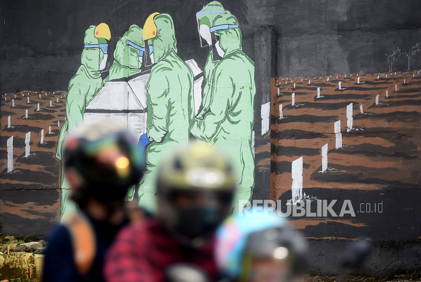 Pengendara motor melitas di depan mural tentang Covid-19 di Jakarta. Pada Selasa (5/1), Satgas melaporkan, kasus baru yang ditemukan mencapai 7.445.