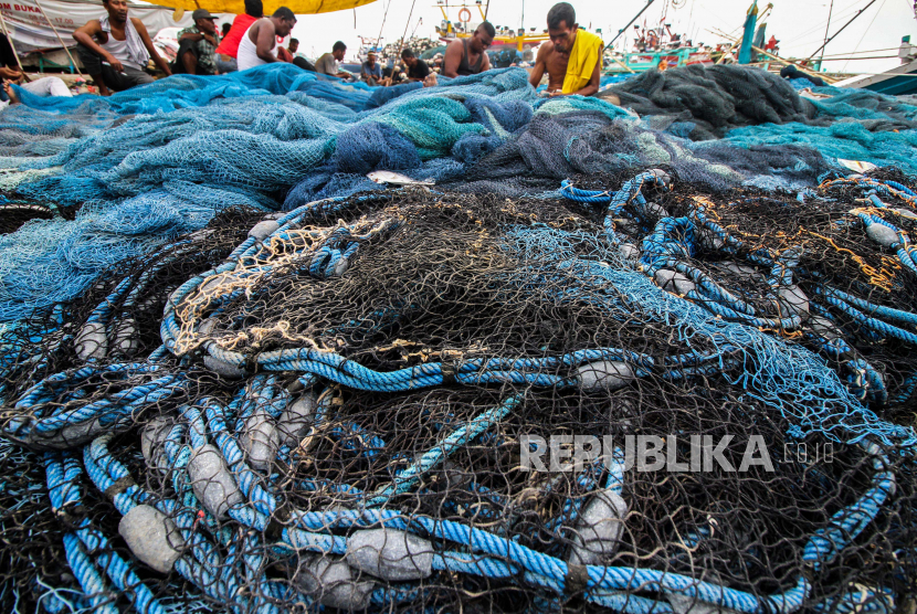Sejumlah nelayan memamfaatkan waktu untuk memperbaiki jaring dengan latarbelakang kapal motor nelayan parkir di Tempat Pendaratan Ikan (TPI) Pusong, Lhokseumawe, Aceh, Rabu (22/4/2020). Dalam rangka merayakan tradisi meugang bersama keluarga dan menyambut bulan  Suci Ramadhan 1441 hijriah, nelayan Aceh mulai libur melaut dan akan kembali melaut pada hari ketiga Ramadhan