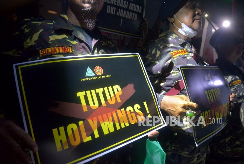 Massa Barisan Ansor Serbaguna (Banser) DKI Jakarta memegang poster melakukan aksi di depan Holywings, kawasan Gunawarman, Jakarta Selatan, Jumat (24/6/2022) malam WIB.