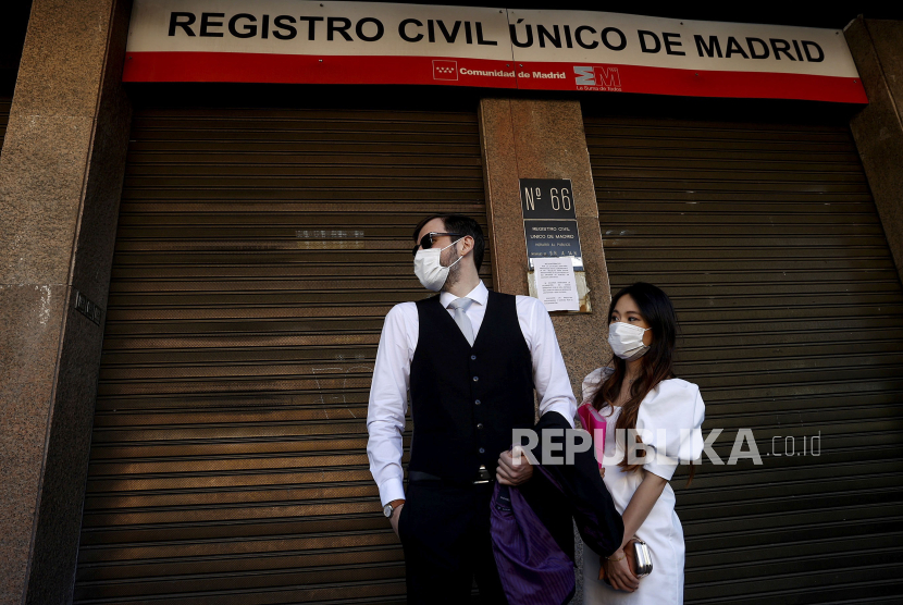 Pengantin pria Rafael (kiri) dan pengantin wanita Miki (kanan) mengenakan masker saat menunggu di luar kantor catatan sipil untuk menikah di Madrid, Spanyol, Jumat (13/3). Pemerintah Madrid memutuskan semua upacara pernikahan harus diadakan tertutup karena pandemi COVID-19 yang disebabkan SARS CoV-2 virus Corona