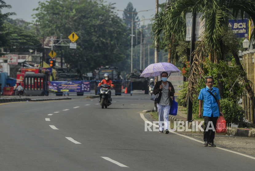 Warga berjalan di ruas Jalan Raya Bogor-Jakarta yang lengang saat dilakukan penutupan di Depok, Jawa Barat, Selasa (6/7). Kepadatan arus lalu lintas kendaraan di Pos penyekatan Pemberlakuan Pembatasan Kegiatan Masyarakat (PPKM) Darurat tersebut sudah berkurang hingga 70 persen pada hari ini. Republika/Putra M. Akbar