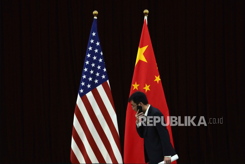 Pejabat China berjalan melewati bendera nasional AS dan China menjelang pertemuan bilateral antara Menteri Keuangan AS Janet Yellen dan Wakil Perdana Menteri China He Lifeng, di Guangdong Zhudao. 