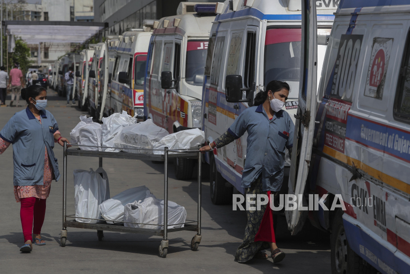 Petugas membagikan  makanan kepada staf ambulans yang membawa pasien COVID-19 saat mengantre menunggu giliran untuk dirawat di rumah sakit pemerintah Covid-19, Ahmedabad, India, Selasa (27/4). Penuhnya rumah sakit membuat para pasien Covid-19 terpaksa harus dirawat di dalam ambulans. Tercatat angka kematian di India akibat virus Covid-19 telah mencapai 200.000 jiwa. (AP Photo/Ajit Solanki)