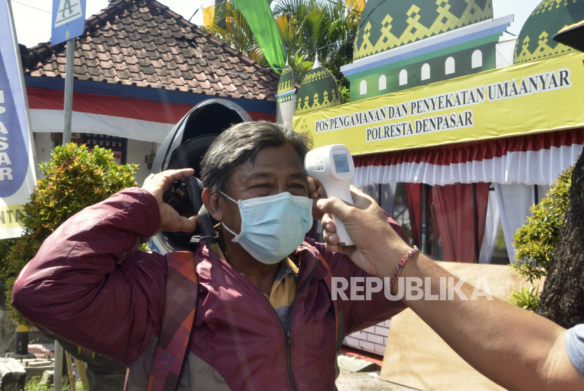Petugas memeriksa suhu tubuh pengendara yang memasuki wilayah Kota Denpasar, di Pos Pengamanan dan Penyekatan Uma Anyar, Denpasar, Bali, Senin (11/5/2020). Pemkot Denpasar terus melakukan persiapan, sosialisasi dan mulai memperketat pintu masuk wilayah Kota Denpasar menjelang penerapan Pembatasan Kegiatan Masyarakat (PKM) di wilayah tersebut pada pertengahan bulan Mei 2020 sebagai upaya pencegahan penyebaran COVID-19