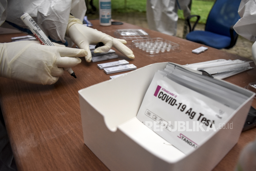 Petugas kesehatan memeriksa sampel lendir pengunjung saat rapid test antigen. 
