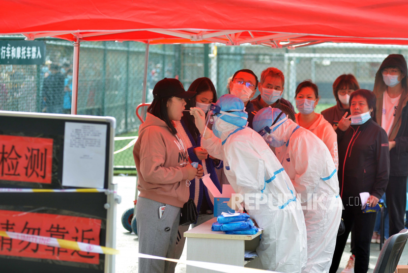  Seorang staf medis mengambil sampel pada warga yang mengantre untuk tes COVID-19 besar-besaran di Qingdao di provinsi Shandong, China timur, China, 12 Oktober 2020. Kota ini akan menguji enam juta warganya dalam tiga hari setelah 12 kasus virus korona yang ditularkan secara lokal COVID- 19 ditemukan.