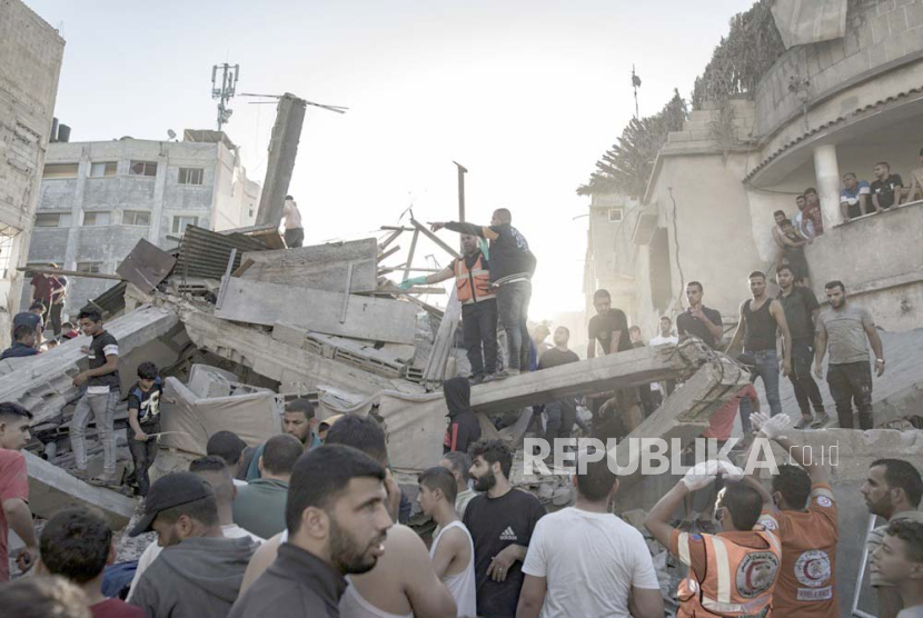 Warga Palestina mencari mayat dan korban selamat di antara puing-puing bangunan tempat tinggal menyusul serangan udara Israel di kamp pengungsi Khan Younis di Jalur Gaza selatan, Palestina, 4 November